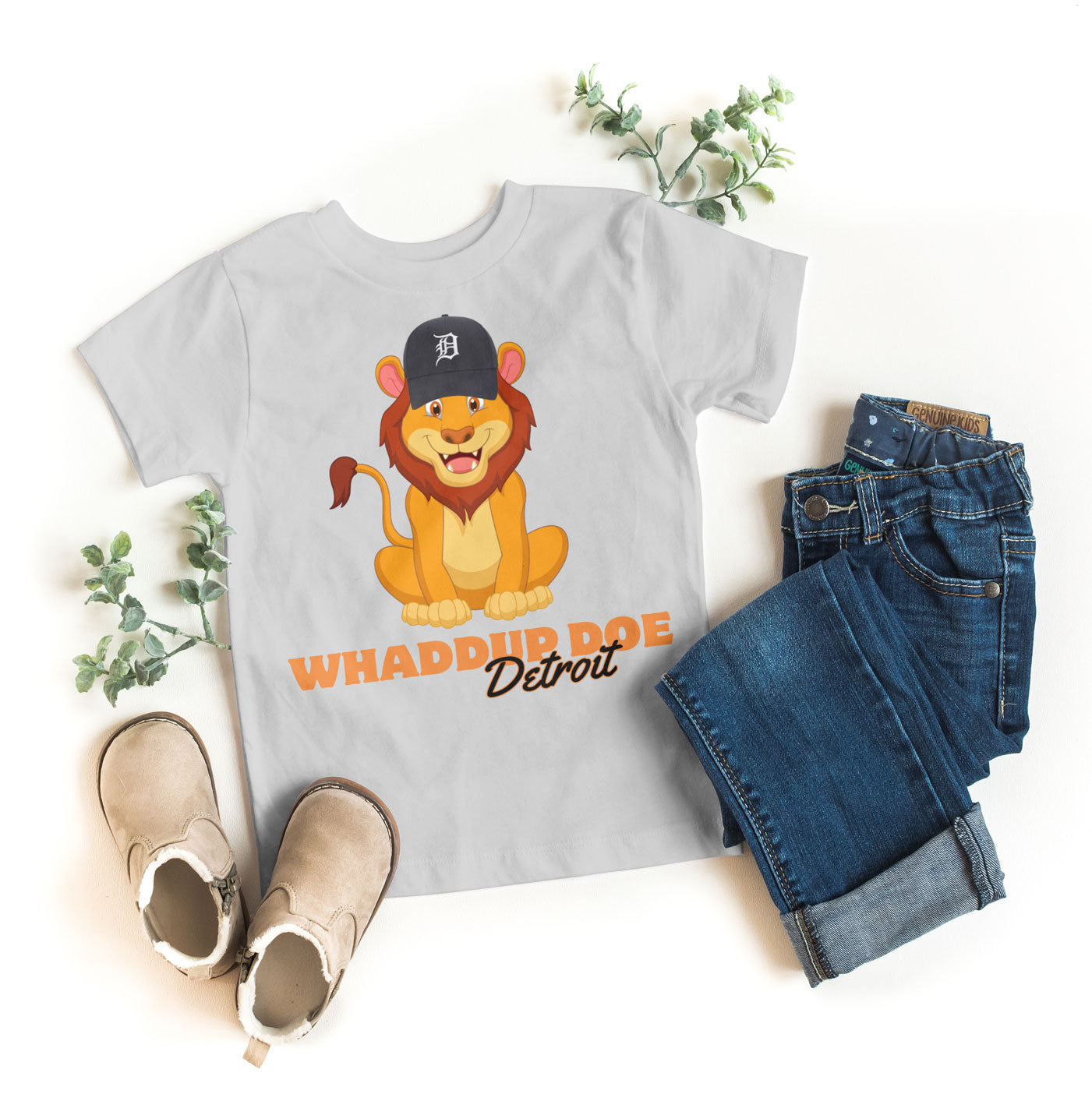 Gray t-shirt with cartoon lion graphic and text, paired with jeans and shoes on a white background.