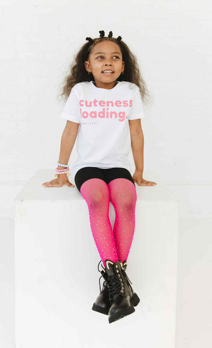 A child wearing a white t-shirt with a graphic word  print saying "Cuteness Loading".