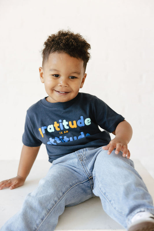 Young child wearing blue gratitude is attitude tee
