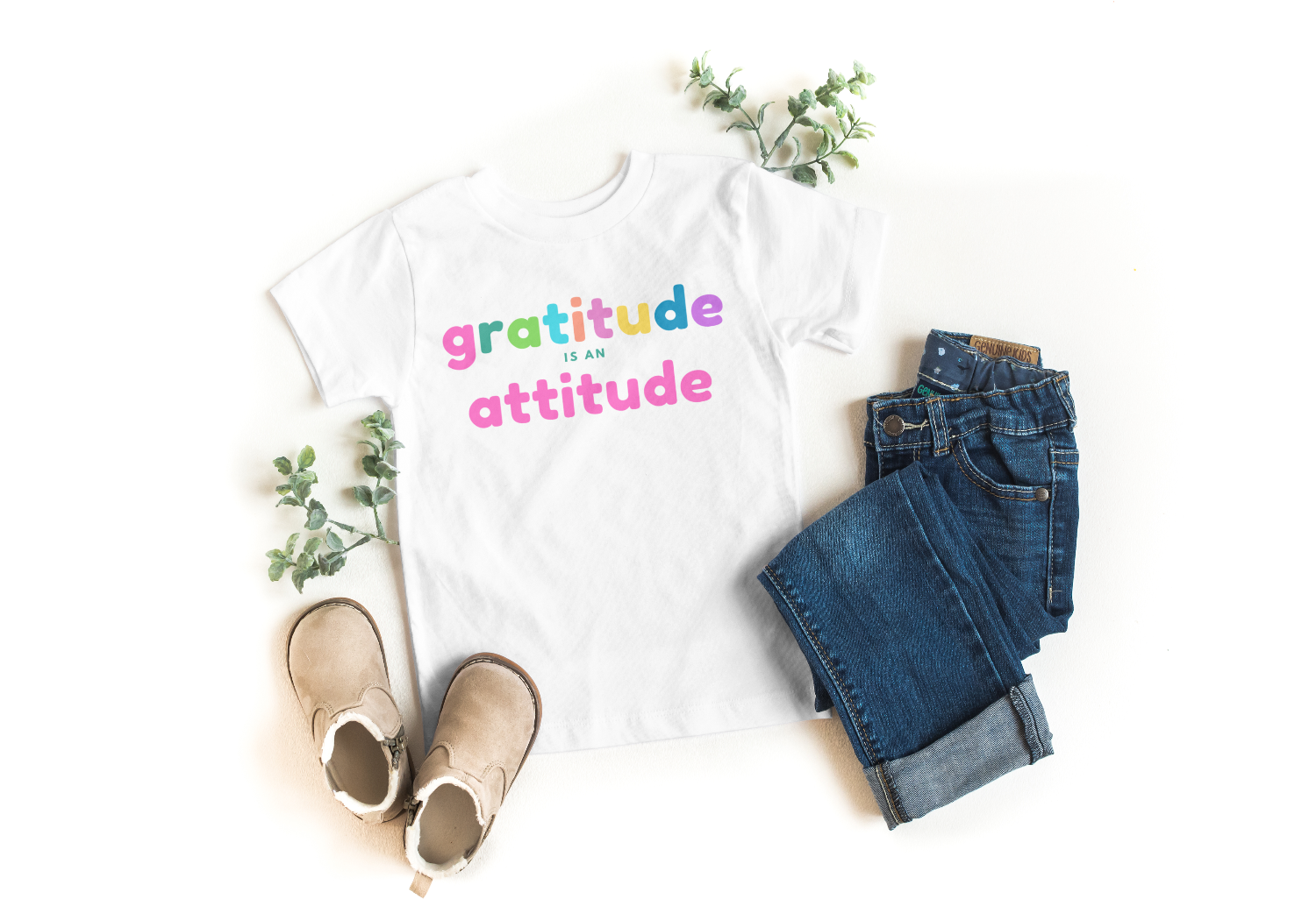 White t-shirt with 'gratitude is an attitude' text, paired with jeans and shoes on a white background